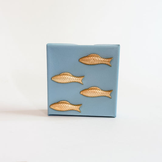 Blue ceramic tile with gold fish designs on a white background