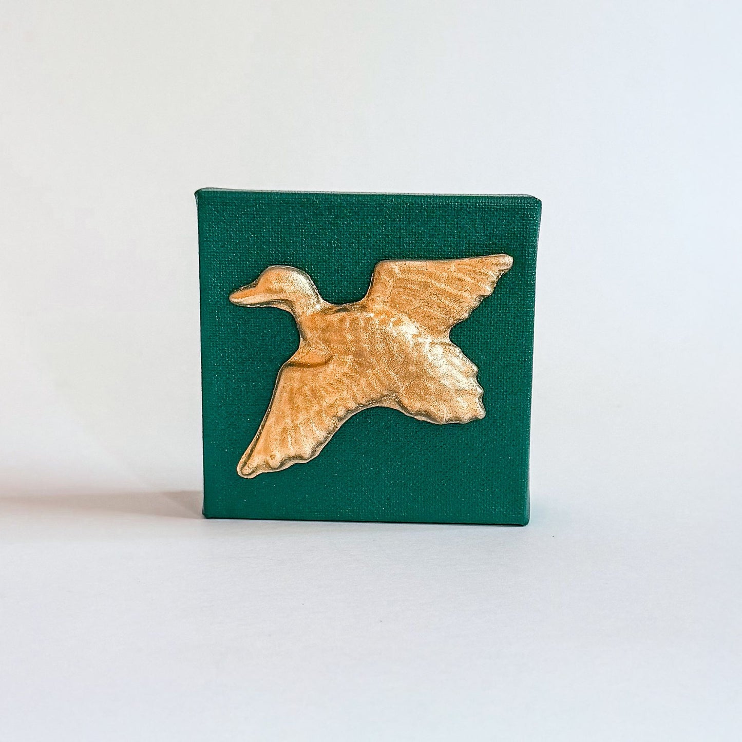 Gold duck-shaped object on a green square background