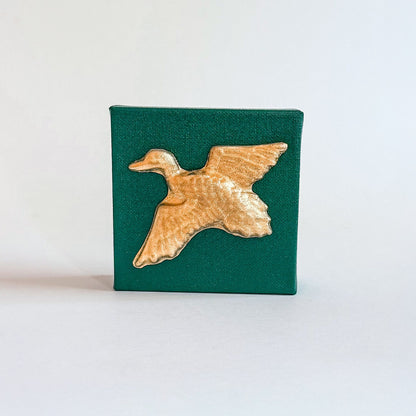 Gold duck-shaped object on a green square background