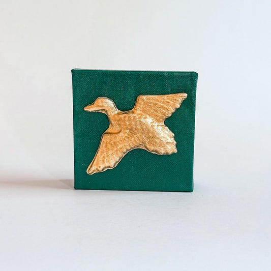 Gold duck-shaped object on a green square background