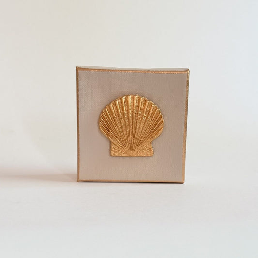 Square beige clutch with a gold shell design on a light gray background