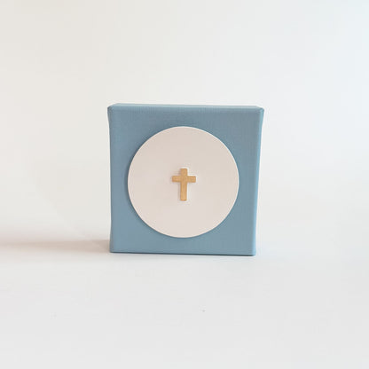 Small blue box with a white circle and gold cross on a light blue background