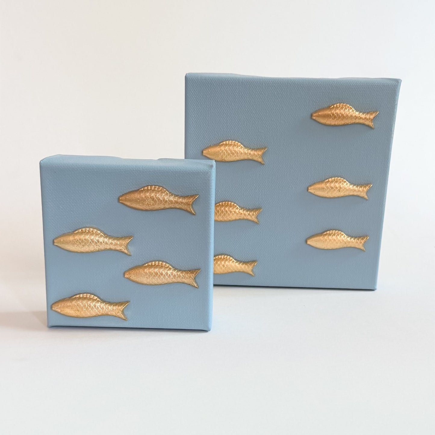 Two blue boxes with gold fish designs on a light gray background