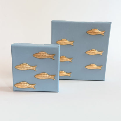Two blue boxes with gold fish designs on a light gray background